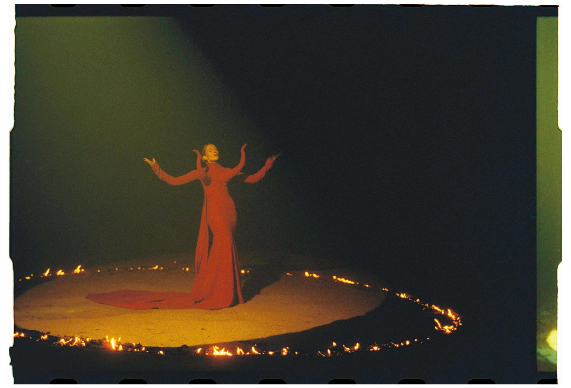 Celine Van Heel con vestido rojo en un círculo de fuego durante escena del videoclip Mi Mentira, 35mm analógico