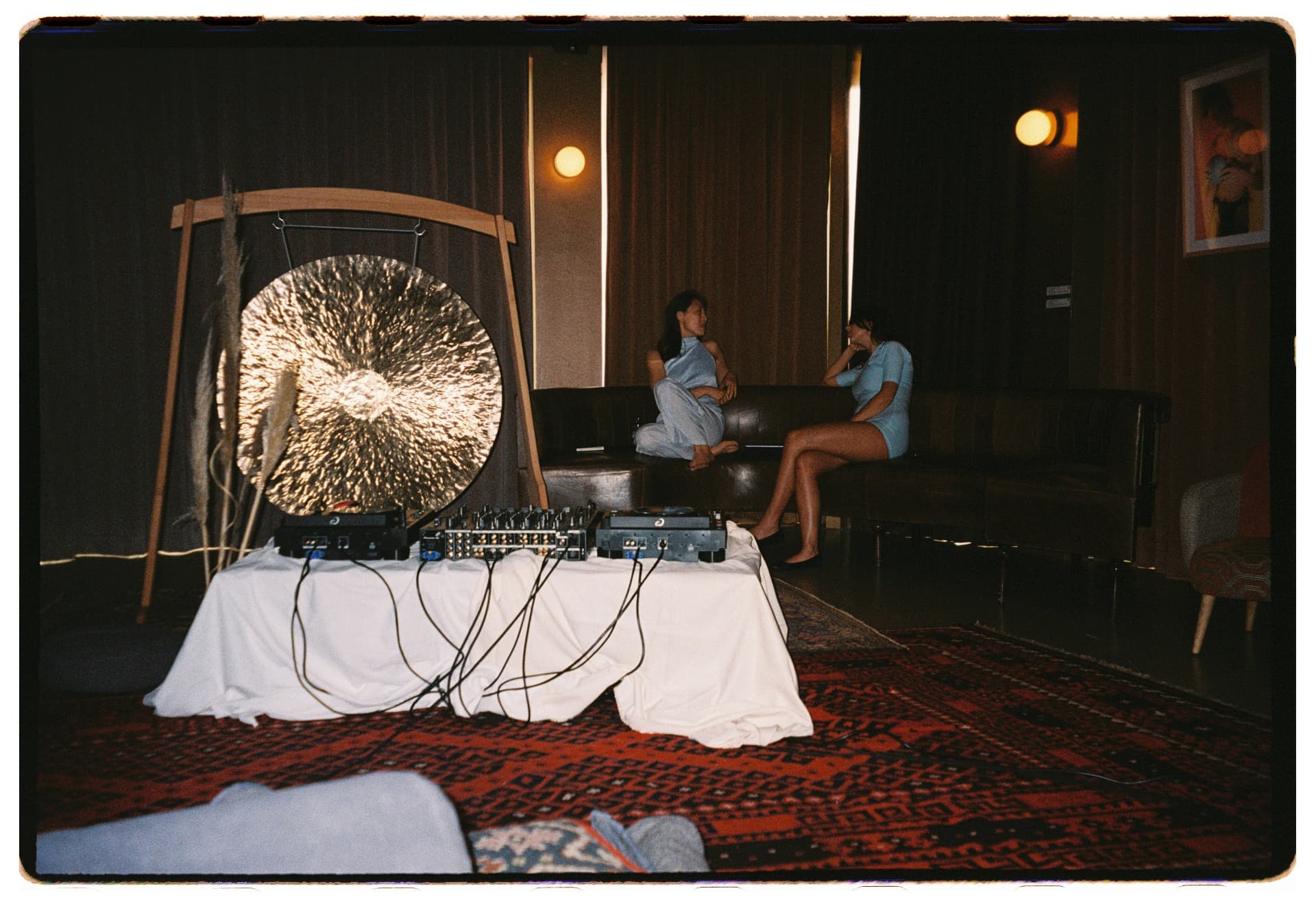 Anfitrionas conversando en el sofá junto al gong y la cabina, La Siesta Hotel Nomade Madrid fotografía analógica