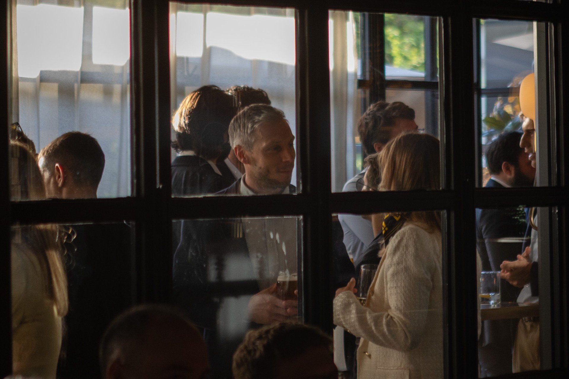 Invitados conversando tras los ventanales del restaurante Tatel Madrid durante el evento de Binance Spain