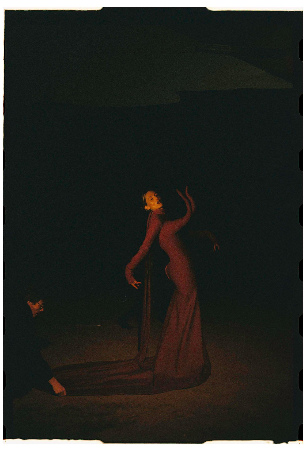 Celine Van Heel con vestido burdeos en movimiento durante escena nocturna, fotografía analógica 35mm