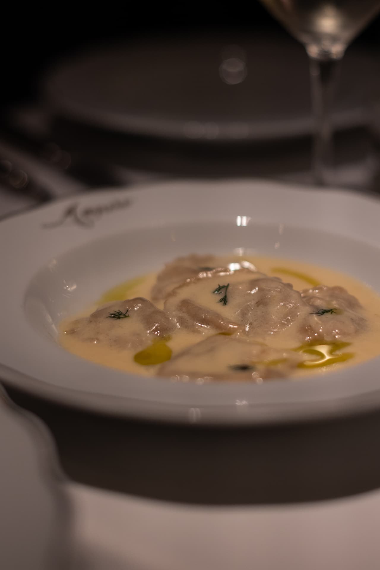 Raviolis en caldo con trufa emplatados en plato hondo en el restaurante Manero Madrid