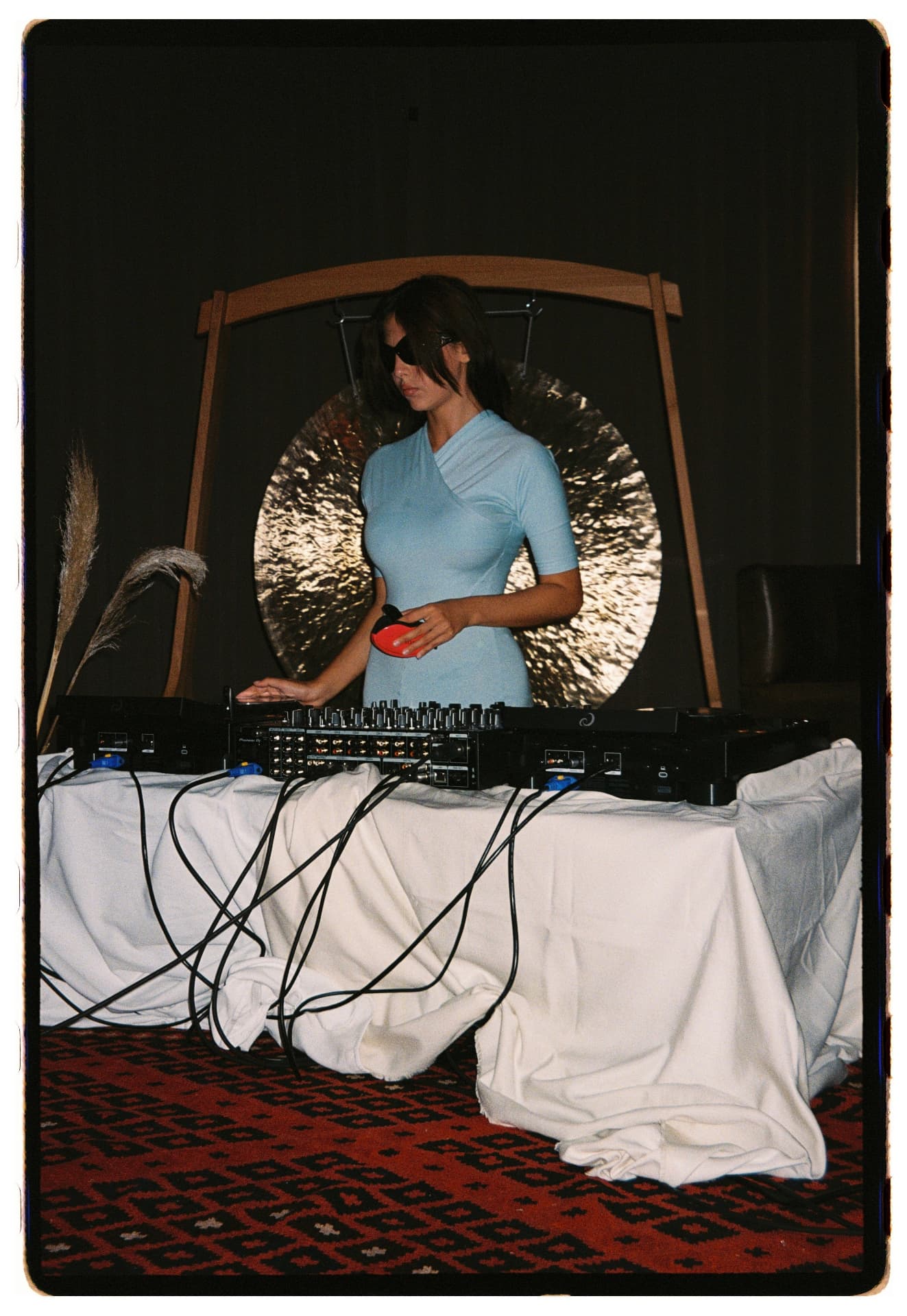 DJ con antifaz y vestido celeste ante el gong durante la sesión, La Siesta Hotel Nomade Madrid fotografía analógica