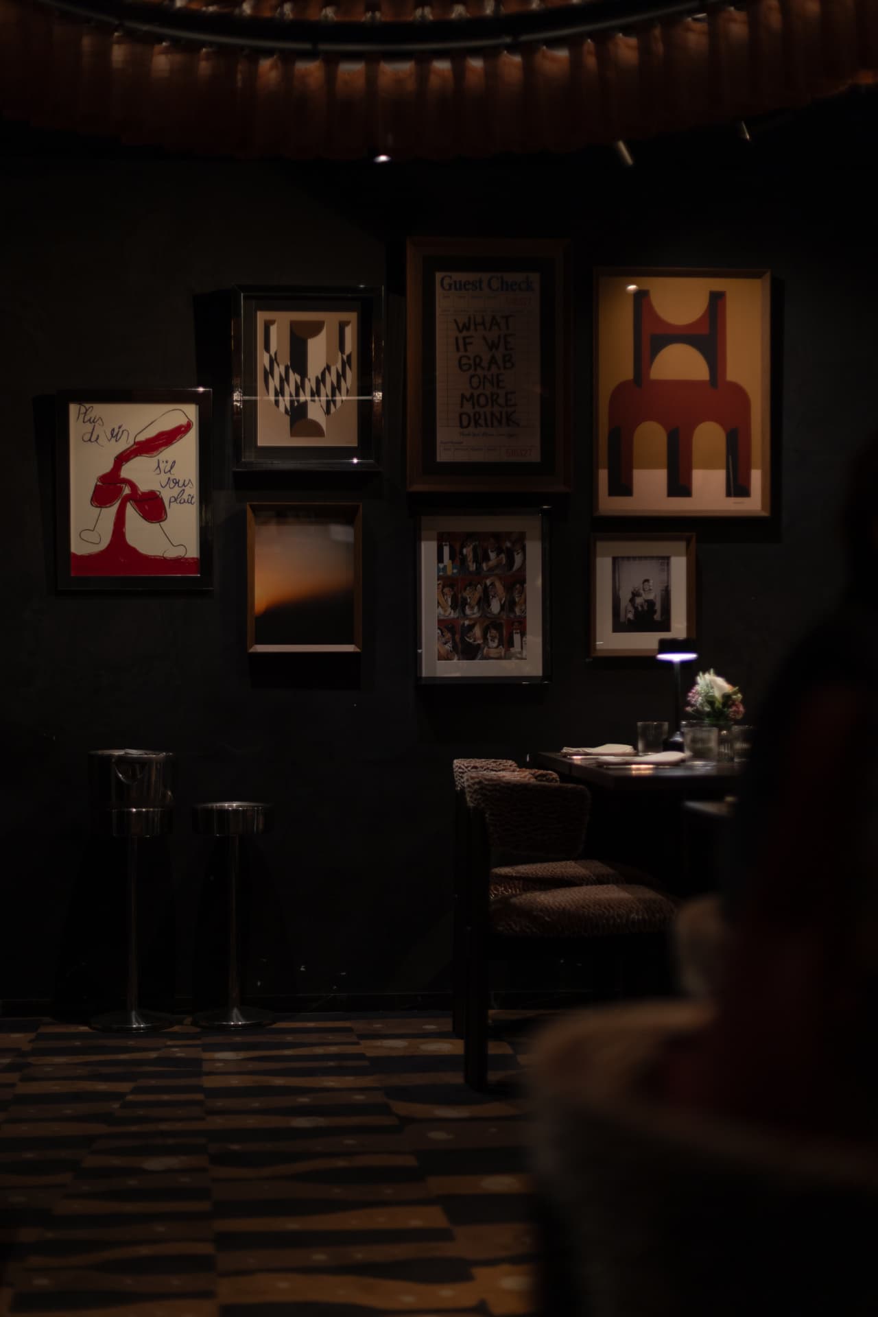 Sala interior de Roostiq Bar Madrid con pared de cuadros y atmósfera íntima de bodega