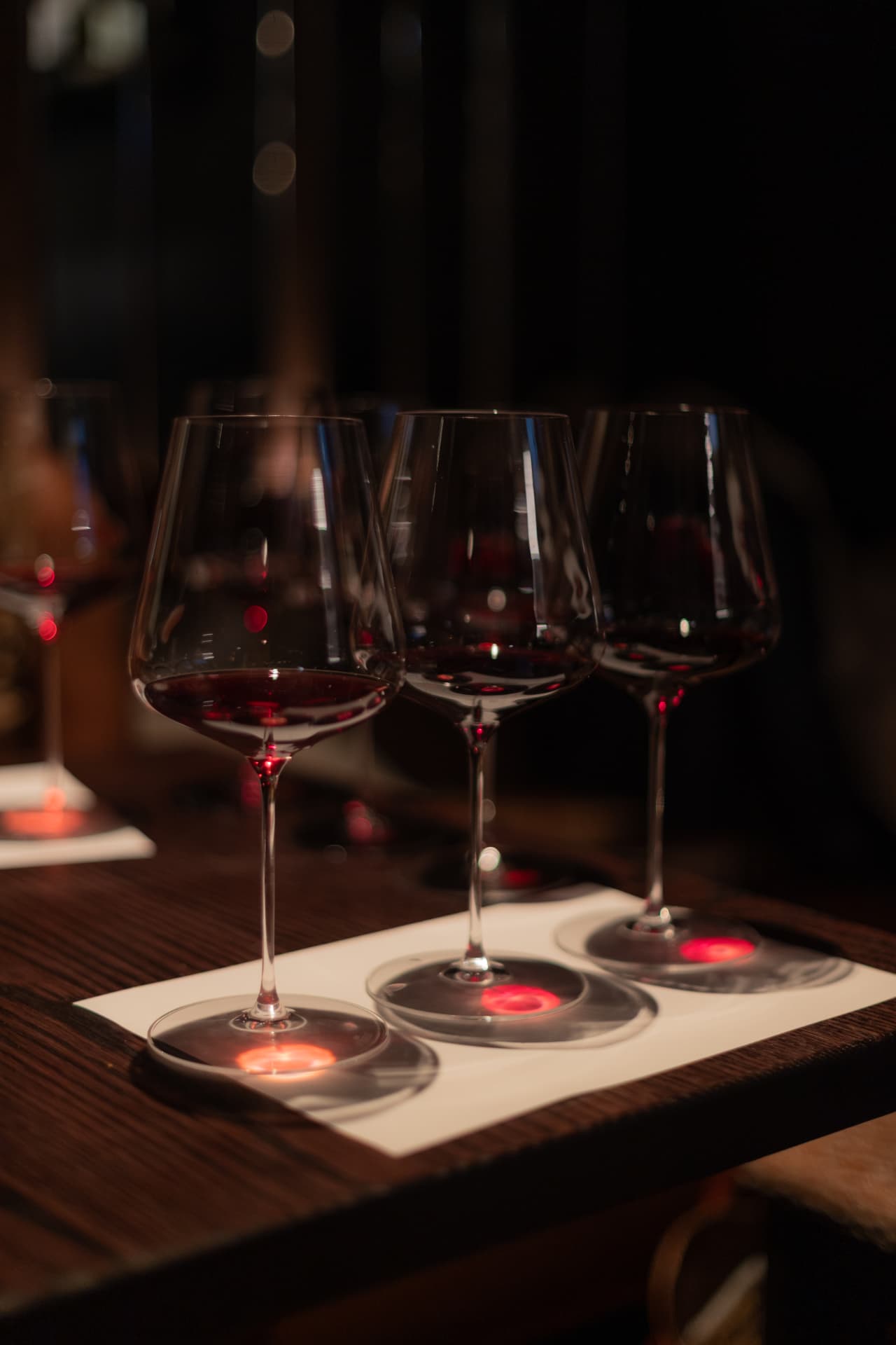 Cata de tres copas de vino tinto sobre mesa de madera en la bodega de Roostiq Bar Madrid