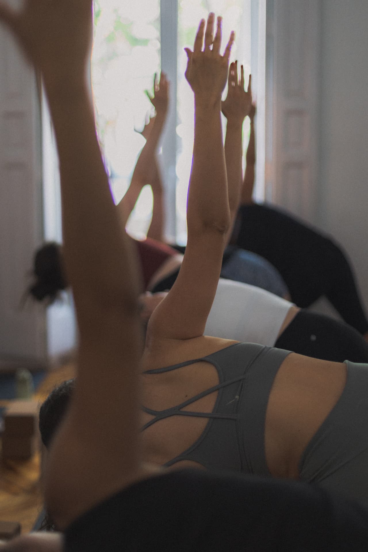 Manos elevadas hacia la ventana durante la práctica en comunidad en Asana Groove Madrid