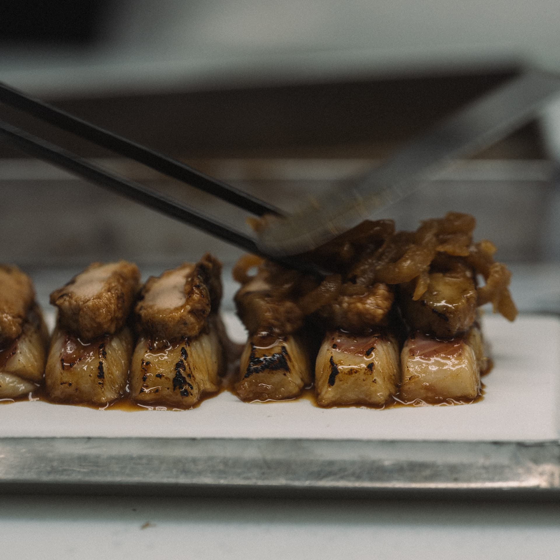 Panceta glaseada laqueada servida con pinzas en la barra de Sala de Despiece Madrid