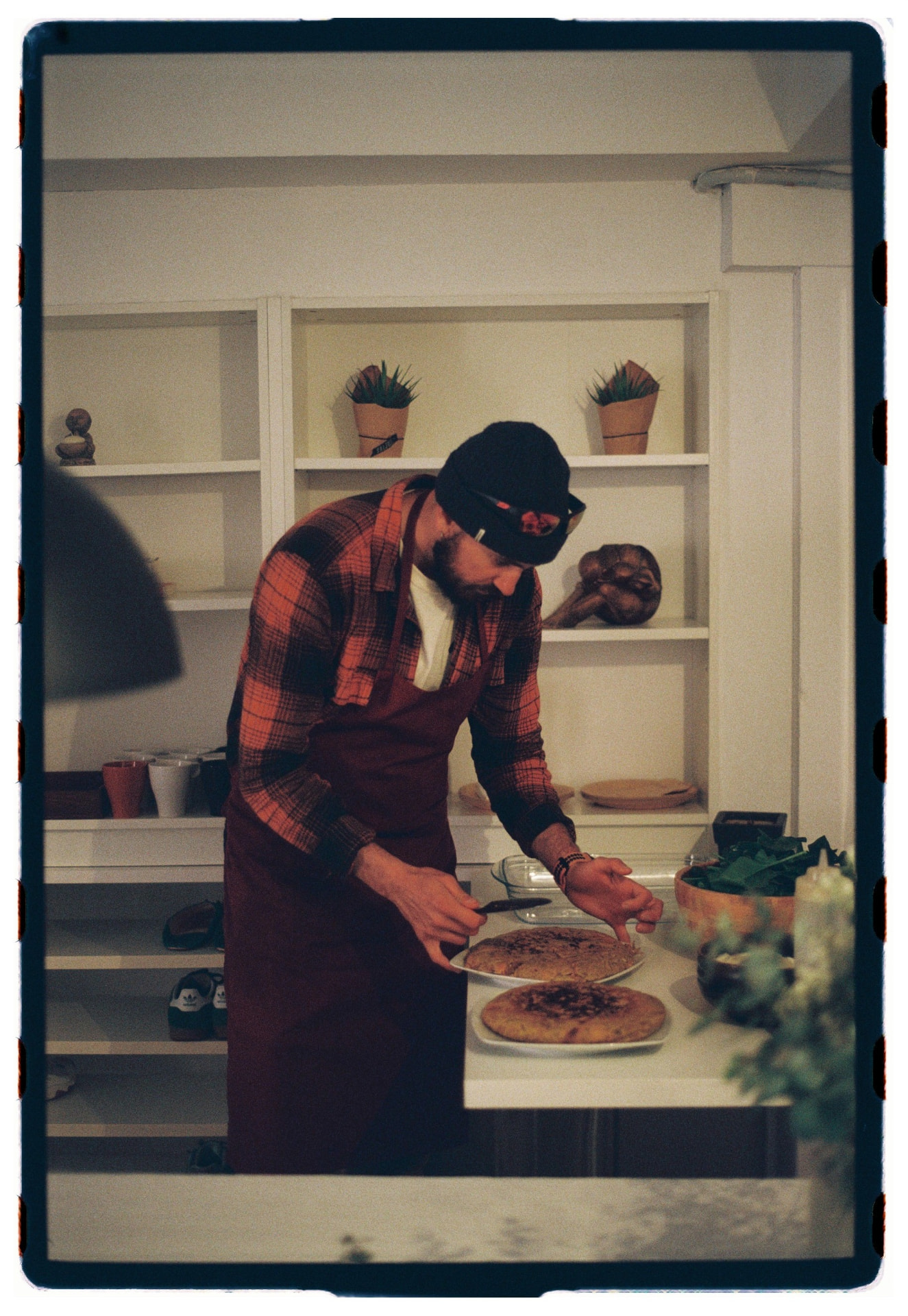 Cocinero con delantal granate emplatando tortillas durante el brunch tras la sesión de vinyasa, fotografía analógica Madrid