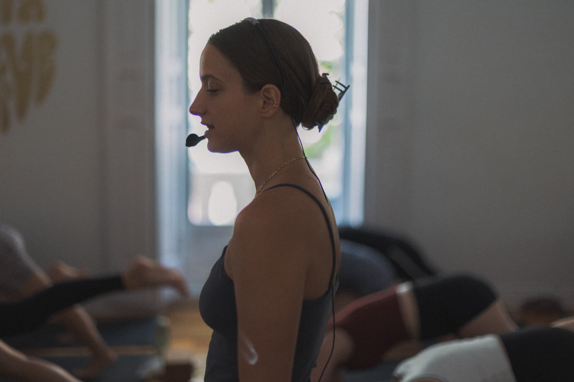Profesora de perfil con micrófono guiando una clase en el estudio de yoga Asana Groove Madrid
