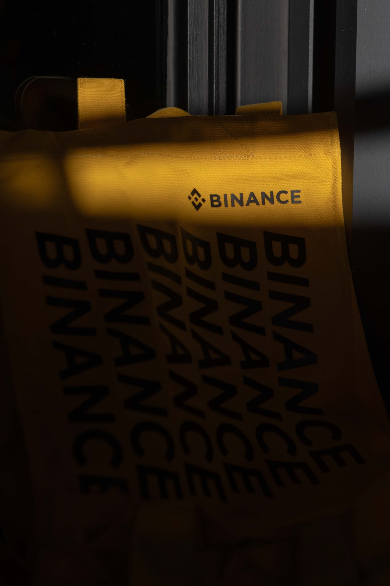Tote bag corporativa con branding de Binance iluminada por luz cálida en el evento de Tatel Madrid