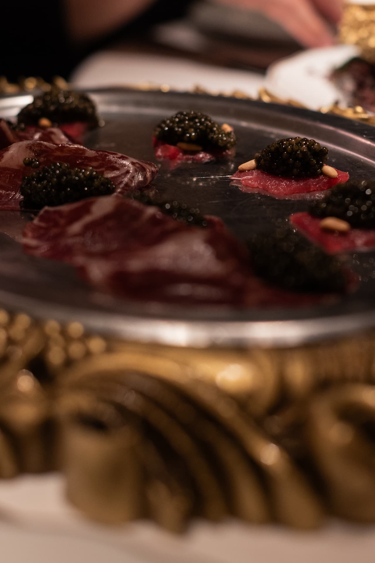 Bandeja de cecina con caviar sobre marco dorado en el bistró de champagne y caviar de Manero