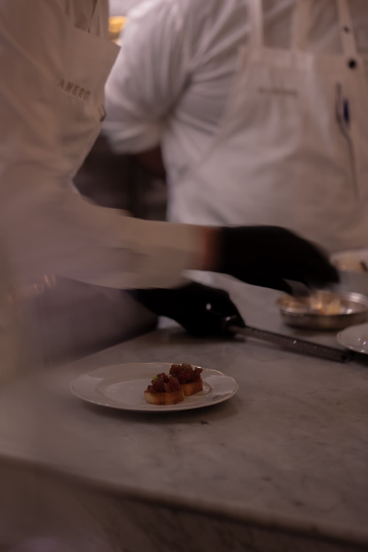 Cocineros de Manero terminando brioches entre humo y ritmo de servicio en cocina
