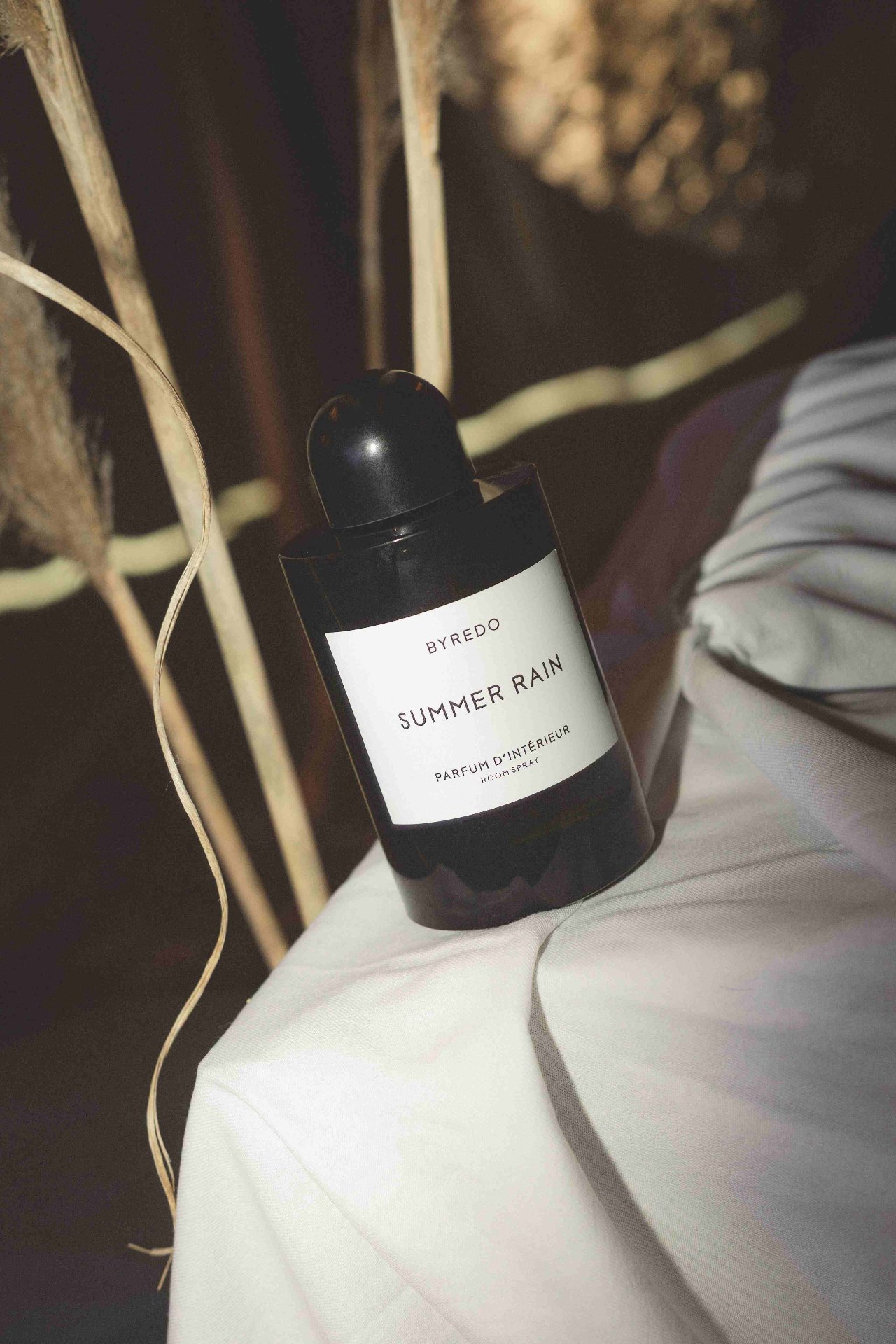 Detalle del perfume Byredo Summer Rain entre pampas y textiles neutros en La Siesta Hotel Nomade Madrid