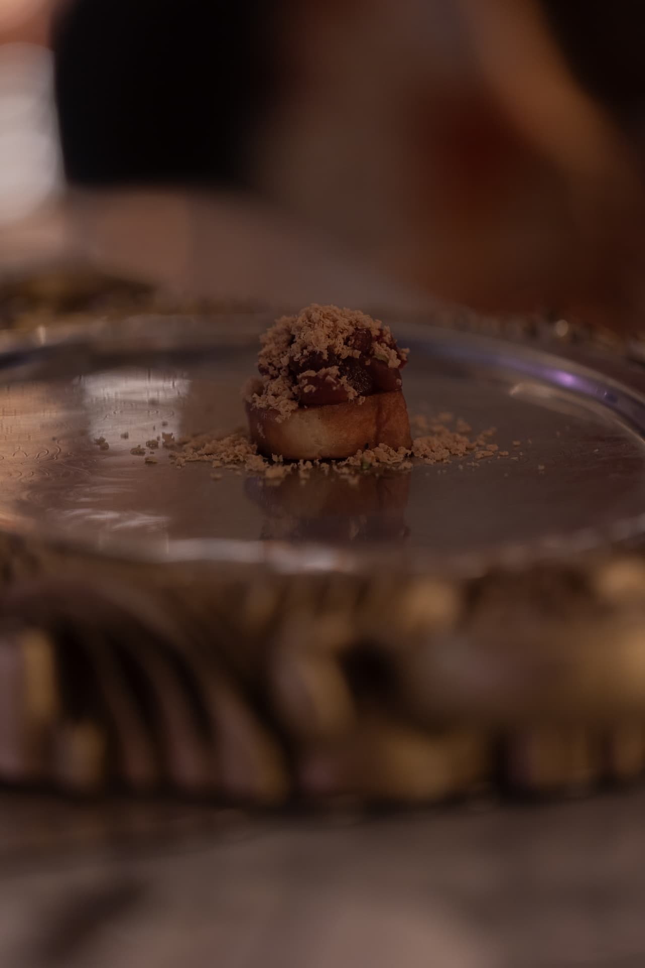 Brioche con tartar y crumble sobre bandeja de plata en el bistró de Manero Madrid