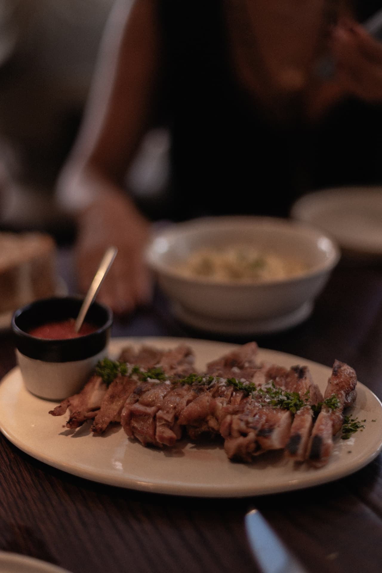 Carne a la brasa con salsa presentada en mesa en Roostiq Bar Madrid