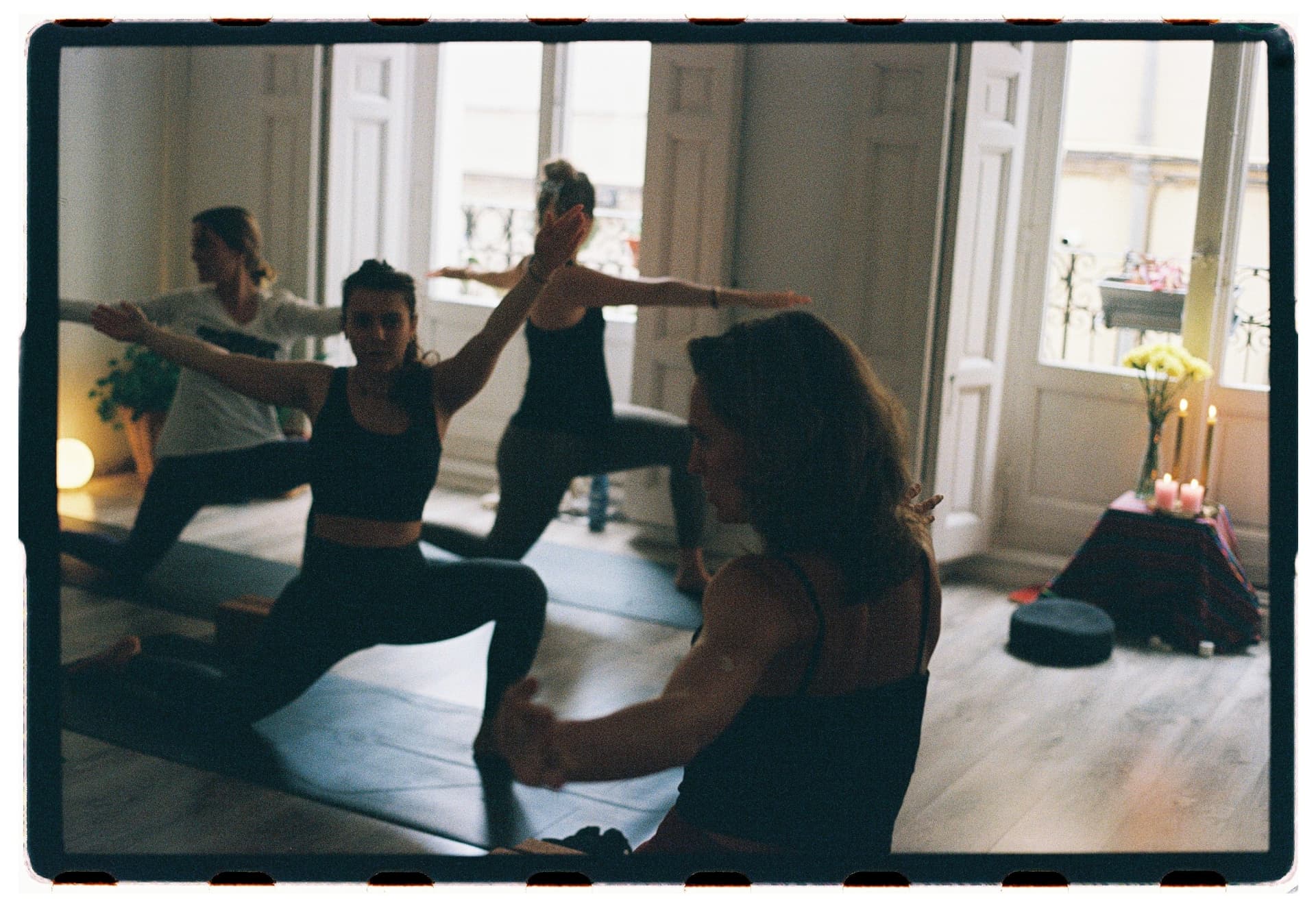 Grupo de alumnas en postura del guerrero reflejadas en el espejo del estudio, sesión Jivamukti Yoga Nidra fotografía analógica Madrid