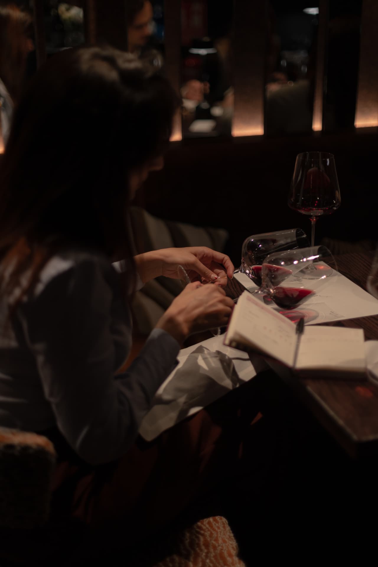 Comensal tomando notas de cata junto a copas de vino tinto en Roostiq Bar Madrid