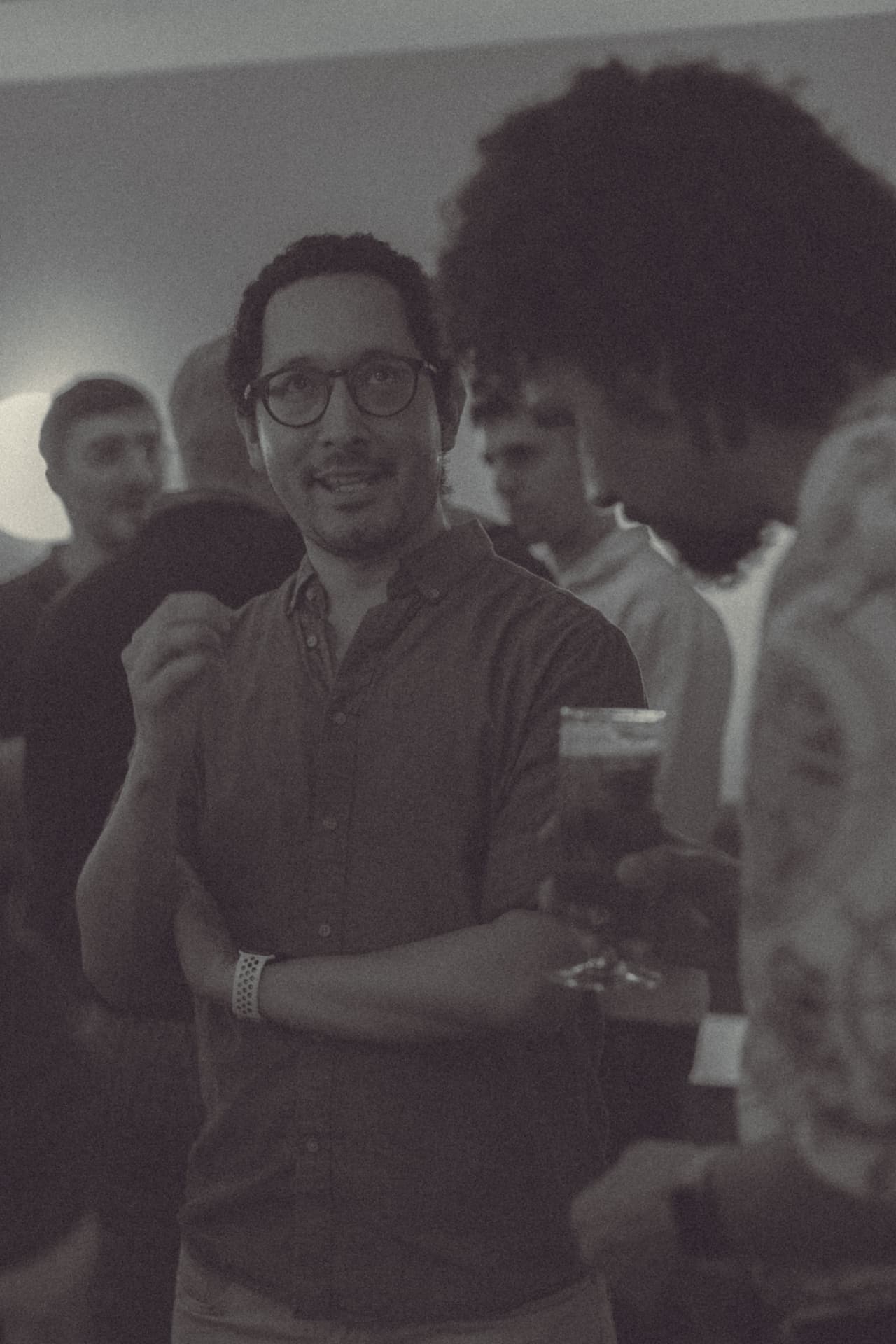 Asistente con gafas sonriendo con copa en mano durante la quedada comunidad Sobremesa tech Madrid diálogo abierto