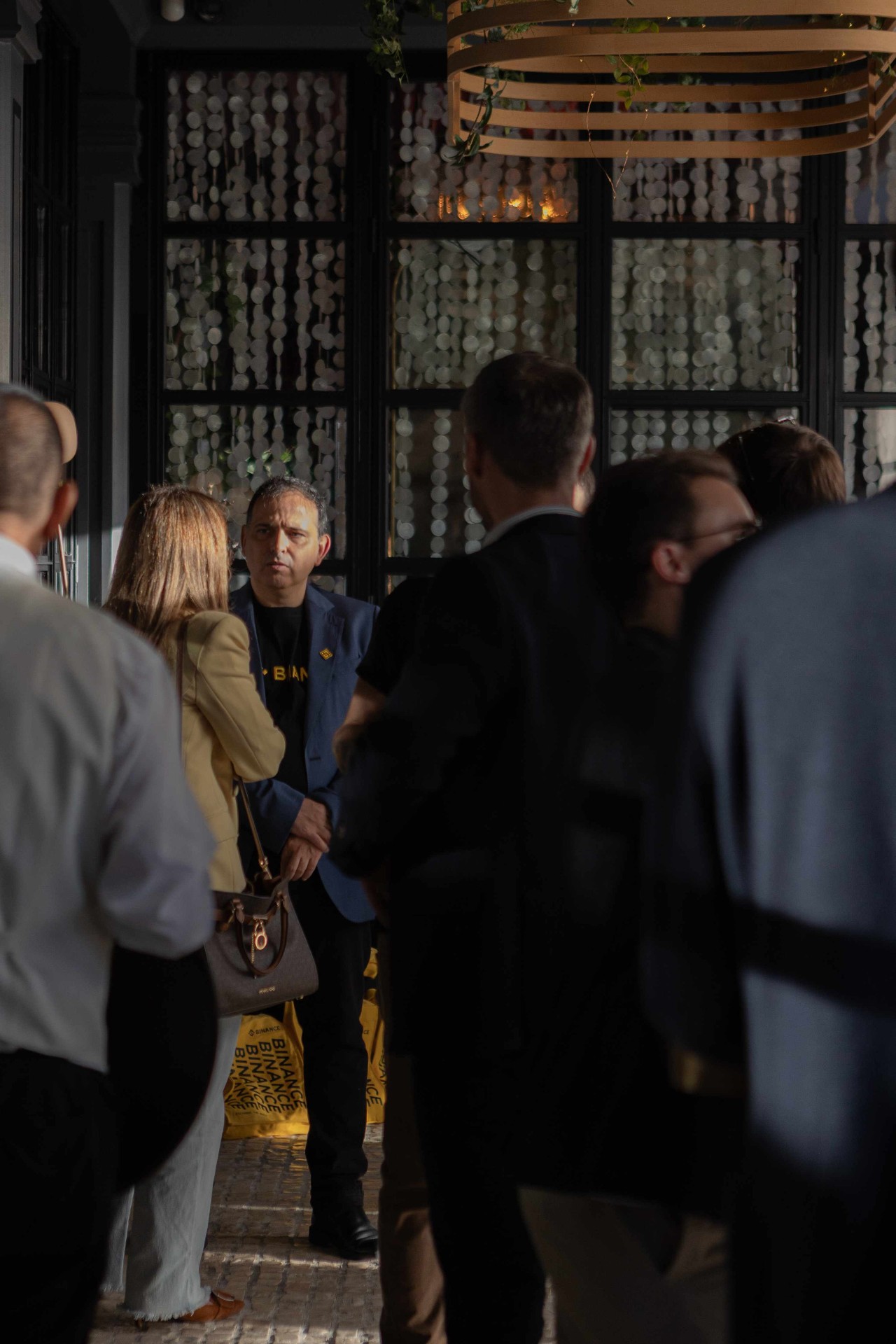 Asistente con camiseta oficial de Binance junto a las bolsas del evento en Tatel Madrid