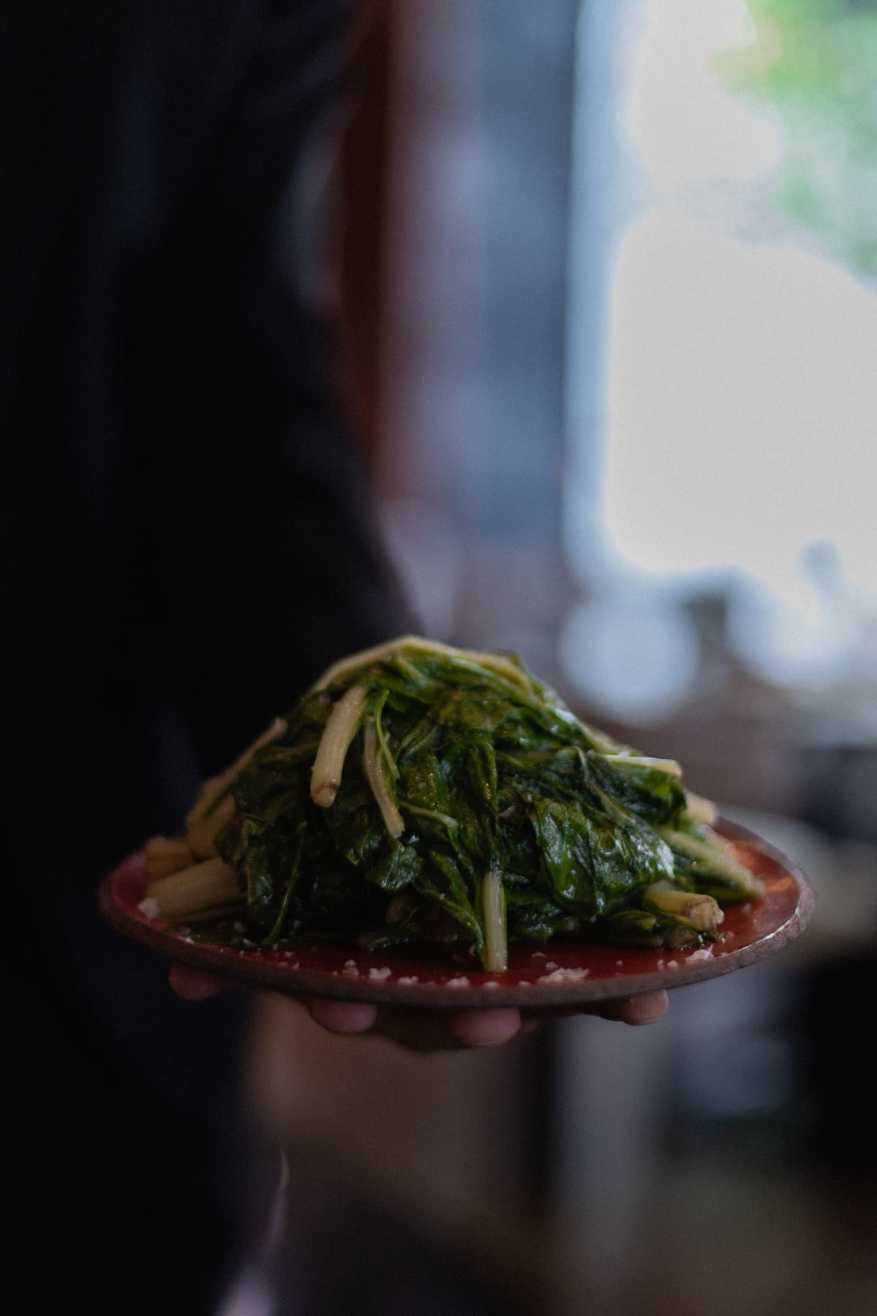 Plato de verduras salteadas de huerta propia servido en mano en Roostiq Bar Madrid