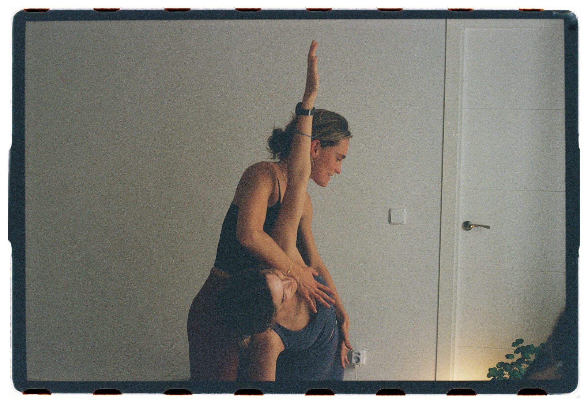 Profesora acompañando una flexión lateral con brazo en alto de una alumna, sesión Jivamukti Yoga Nidra fotografía analógica Madrid